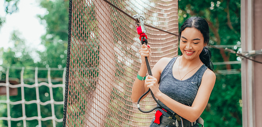 woman clipped to safety harness, preparing for zipline adventure in Singapore