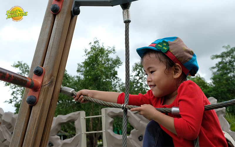 Young girl climbing rope obstacle at Forest Adventure.